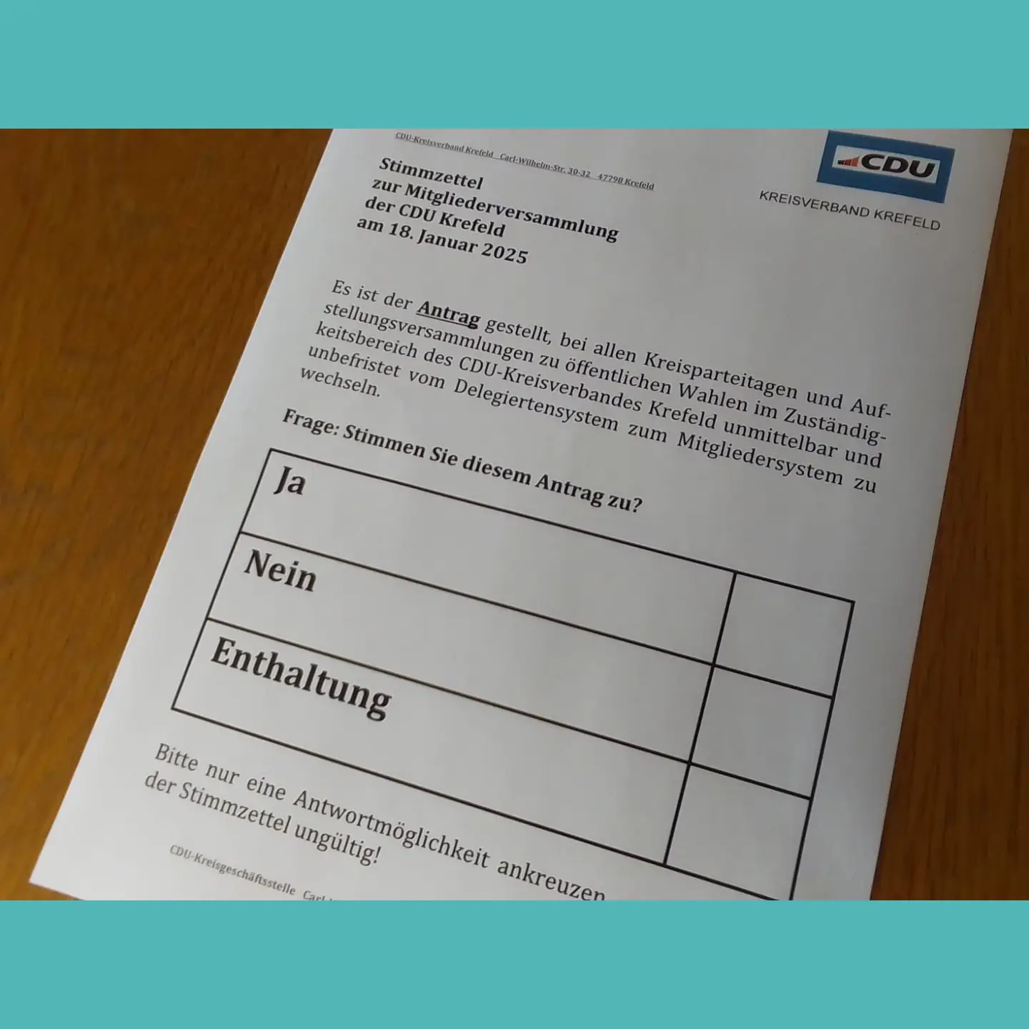 oben und unten das CDU Türkis,
 dazwischen ein Bild von einem Stimmzettel für die Wahl des Mitgliedersystems mit Ankreuzmöglichkeiten für Ja,
 Nein und Enthaltung